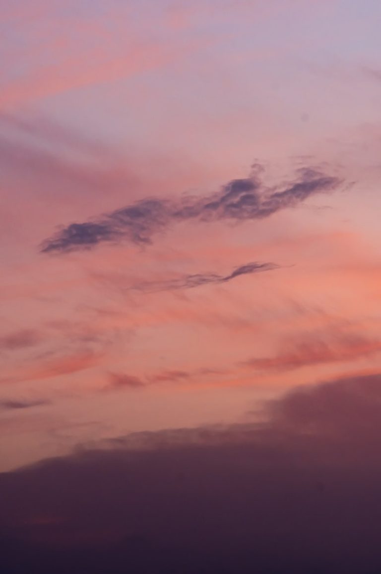 A plane flying in the sky at sunset