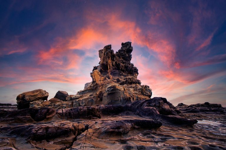 brown rock formation under orange and blue sky