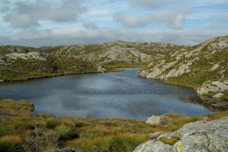 Serene mountain lake surrounded by rocky terrain in Fitjar, Norway. Perfect for nature and travel themes.