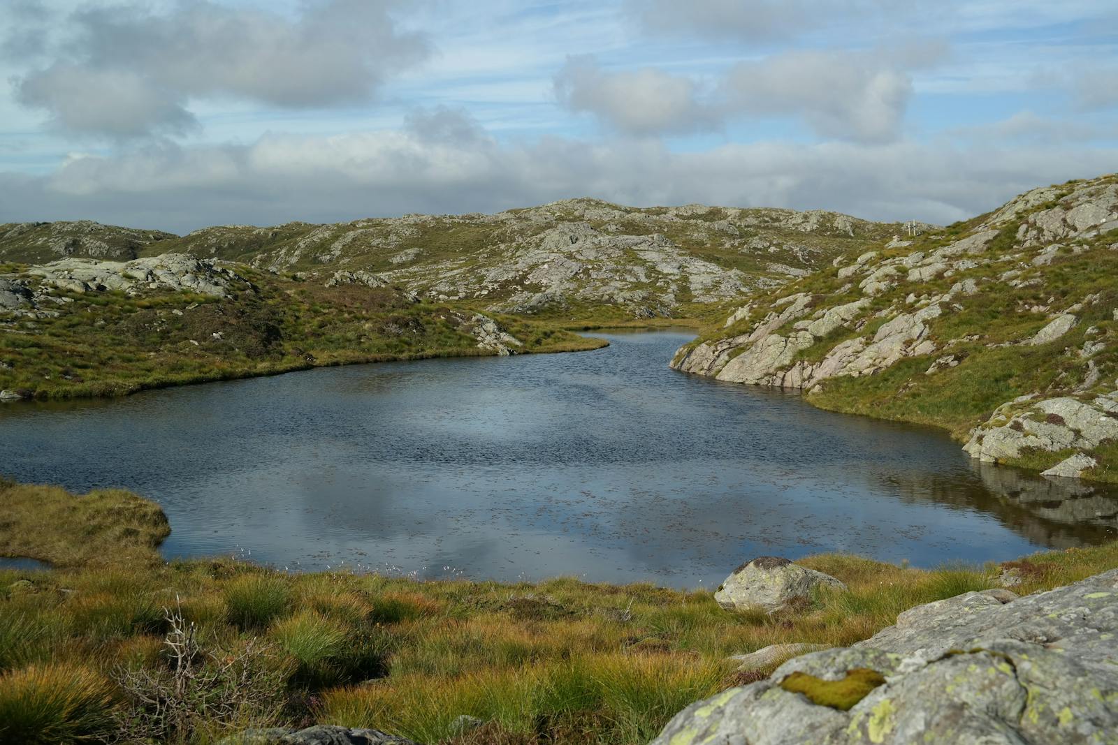 Serene mountain lake surrounded by rocky terrain in Fitjar, Norway. Perfect for nature and travel themes.