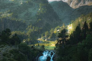a waterfall in the middle of a lush green valley
