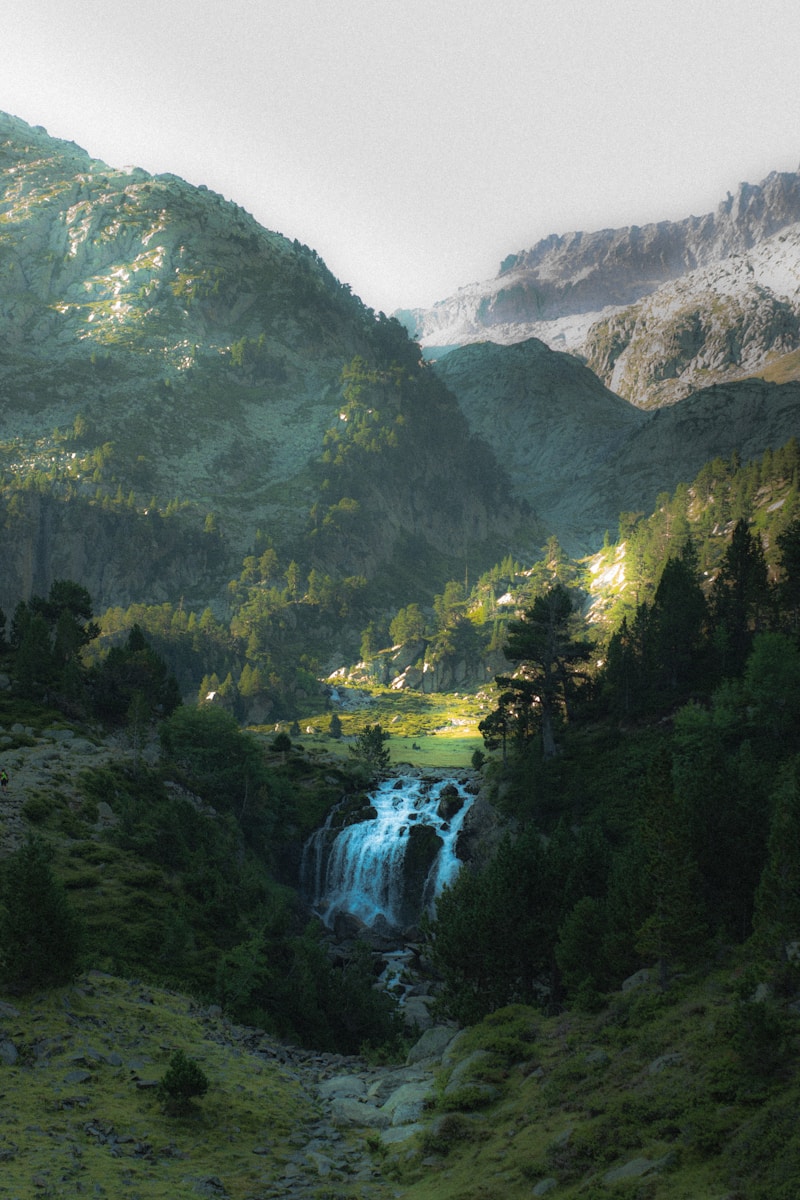 a waterfall in the middle of a lush green valley